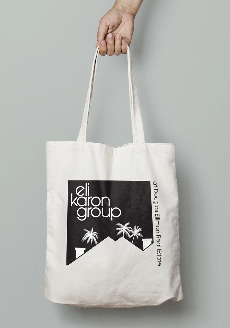 A mockup of a logo design concept for Eli Karon Group on a tote bag.