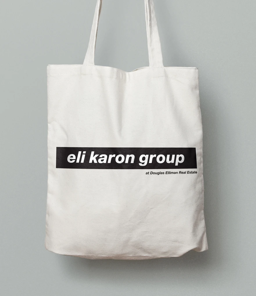 A mockup of a logo design concept for Eli Karon Group on a tote bag in the style of Barbara Kruger.