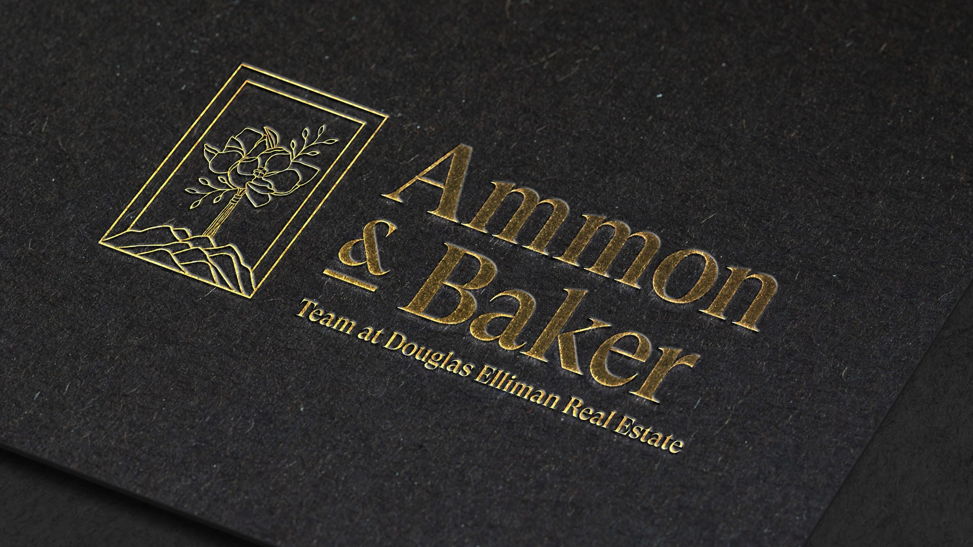 Mockup of Ammon Baker brand identity, Option 1-B in the left lockup as an embossed gold foil on dark paper.