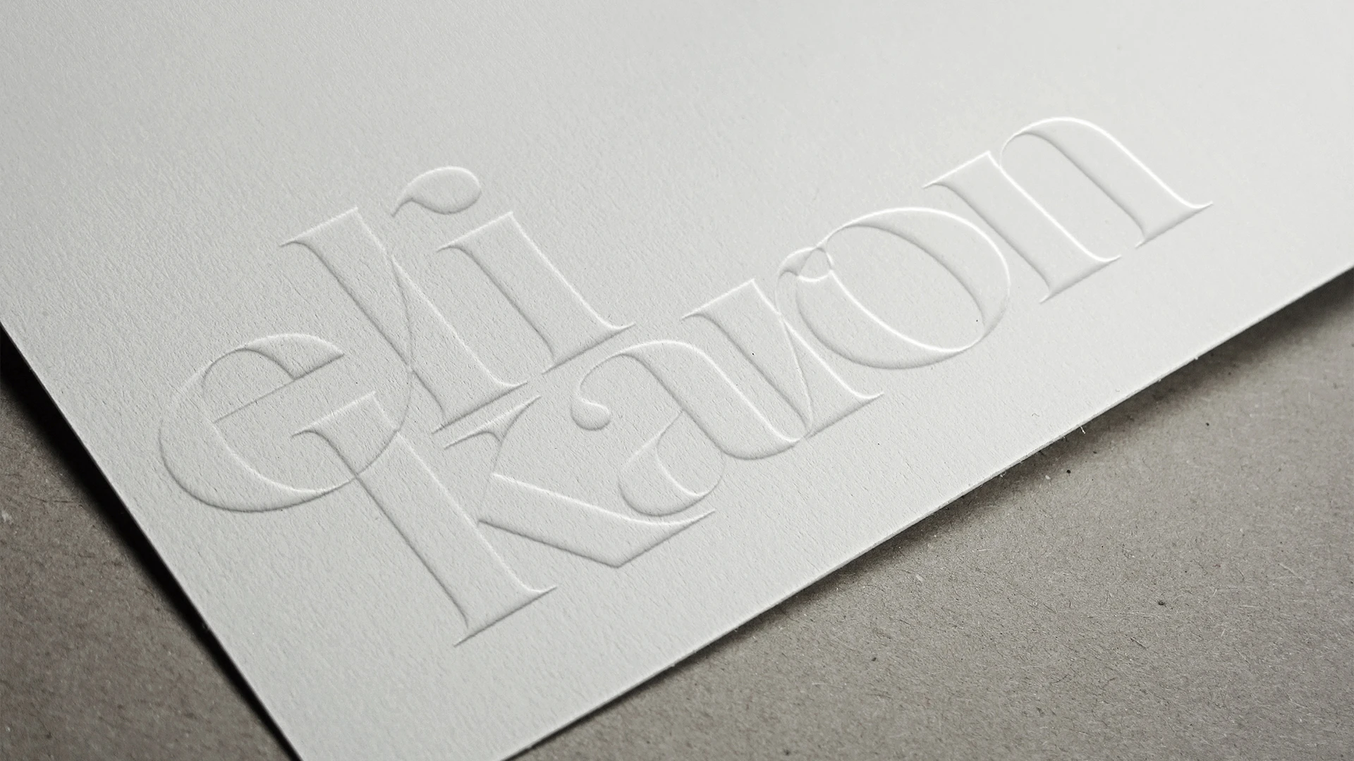Embossed Eli Karon logo on paper.