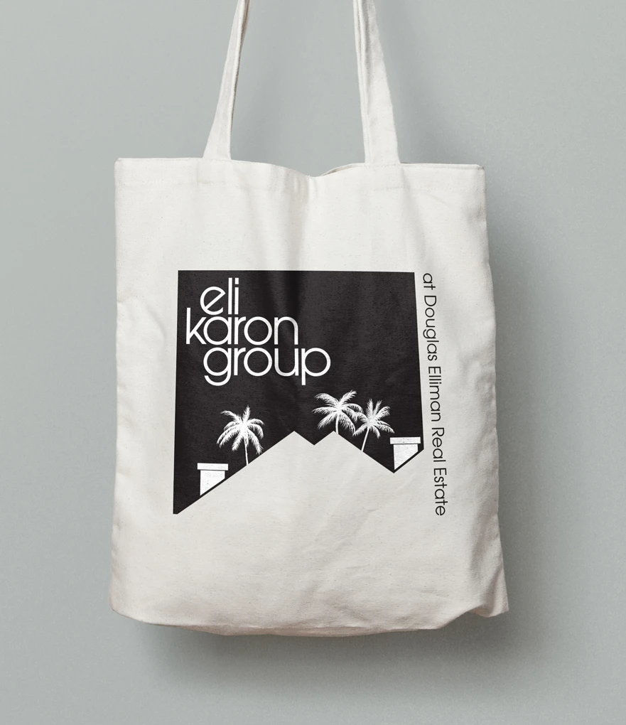 A mockup of a logo design concept for Eli Karon Group on a tote bag.